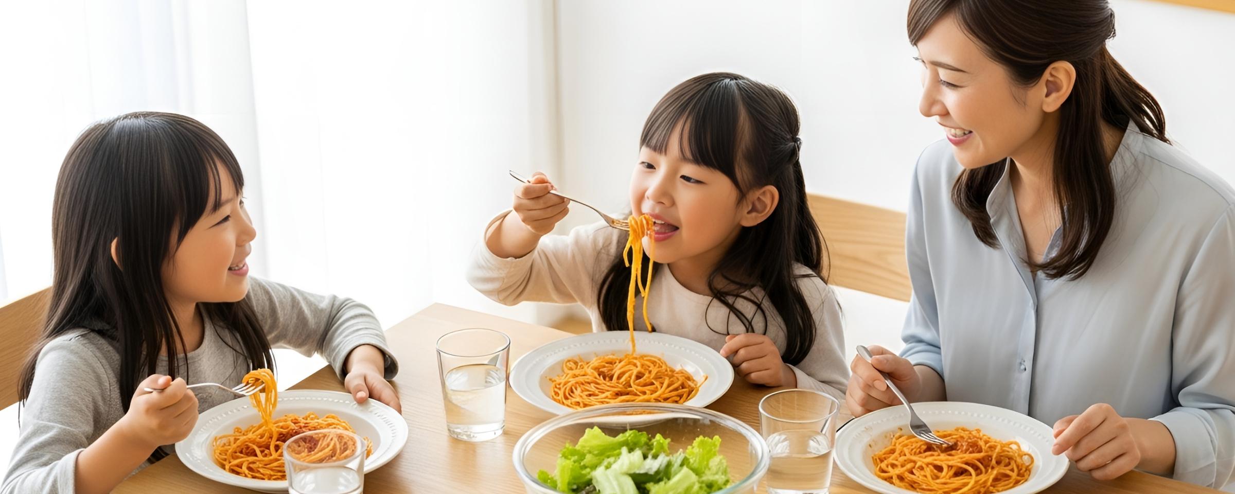サラダとミートソースを食べる娘二人と母親の団欒